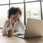 Young multiracial woman in video call taking online classes. Greeting classmates. Waving hand towards laptop. Elearning concept. Working from home. Video call concept.
